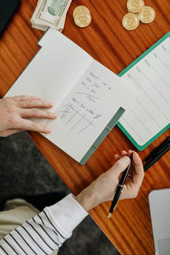 A Person Holding a Pen and Notebook on a Wooden Table
